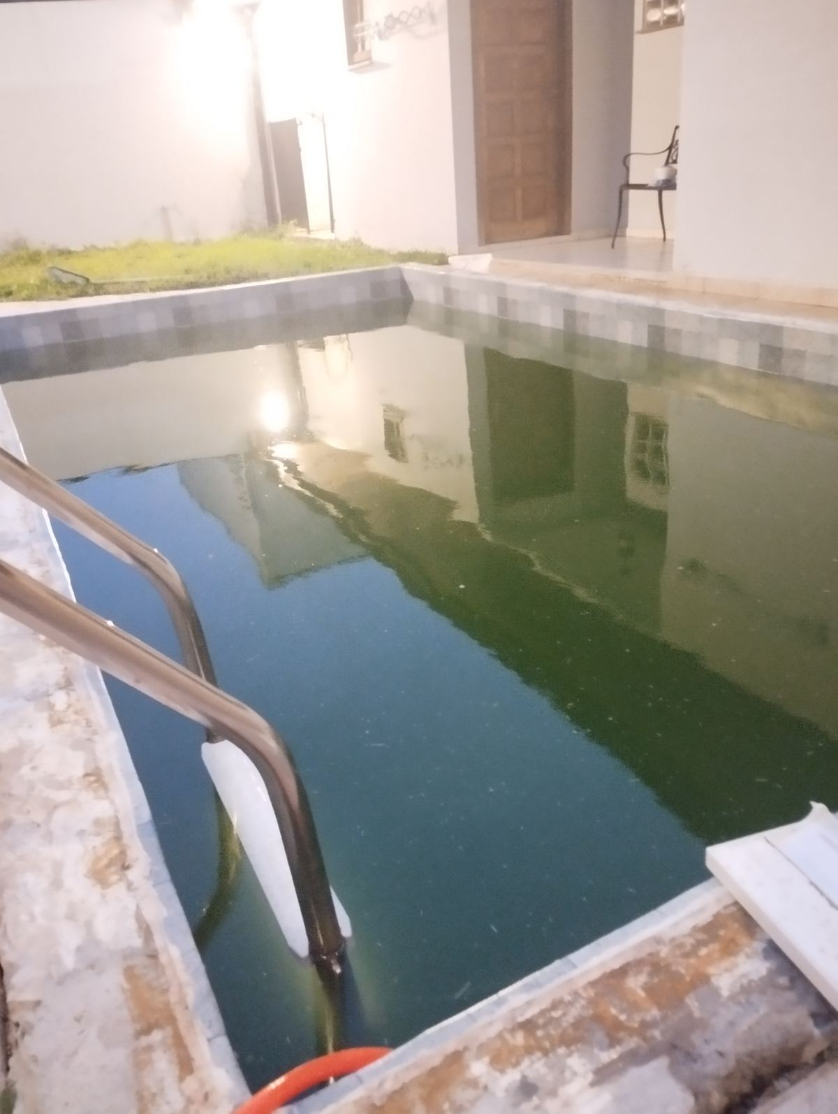 Piscina de alvenaria com escada e água verde