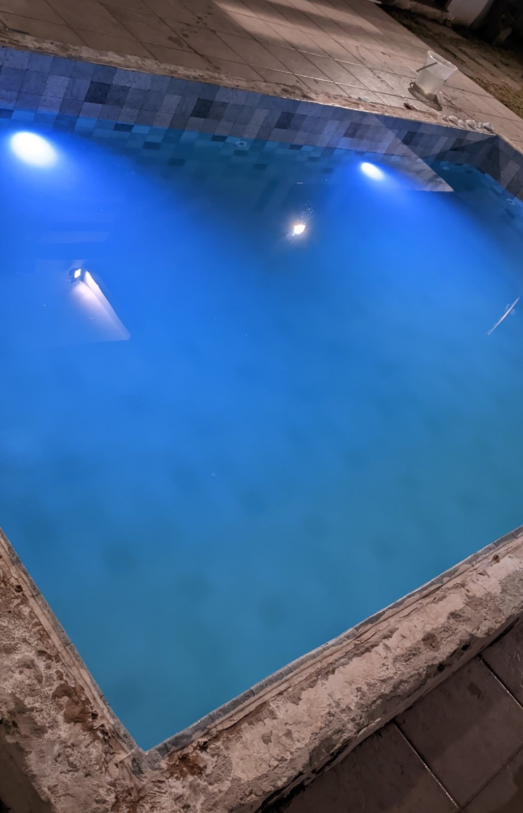A mesma piscina à noite, com as luzes acesas na água azul