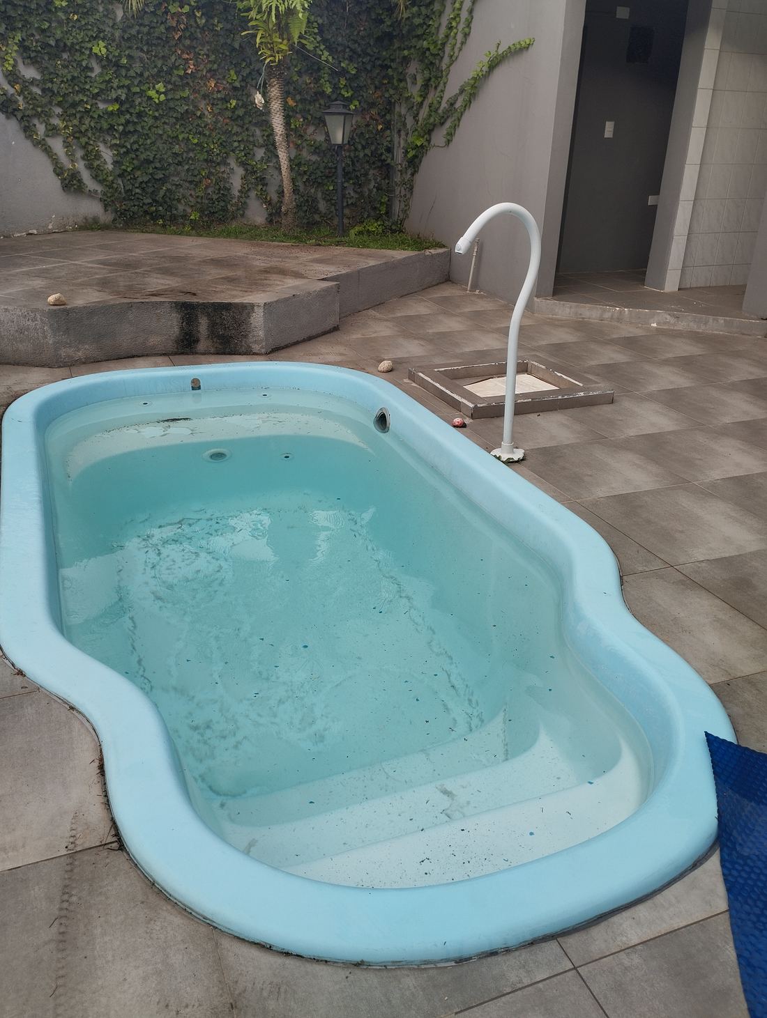 Piscina de fibra com água suja, jato desligado e piso sem acabamento